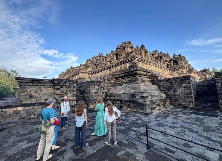 A group of people standing in front of an ancient stone structure with intricate carvings. 3