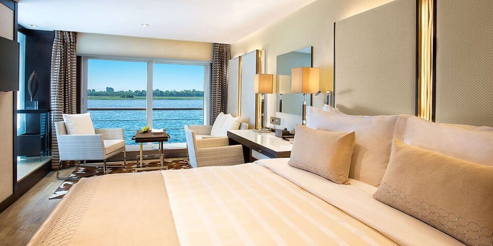 A hotel room with a large bed, a desk, a chair, and a view of a body of water. 5