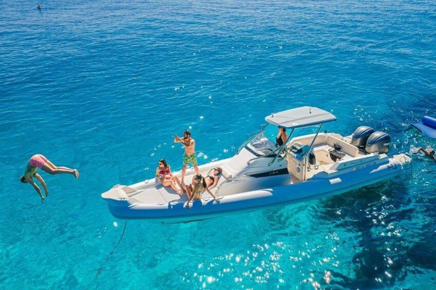 Un bateau avec des personnes à bord, flottant sur une eau d’un bleu limpide. 3