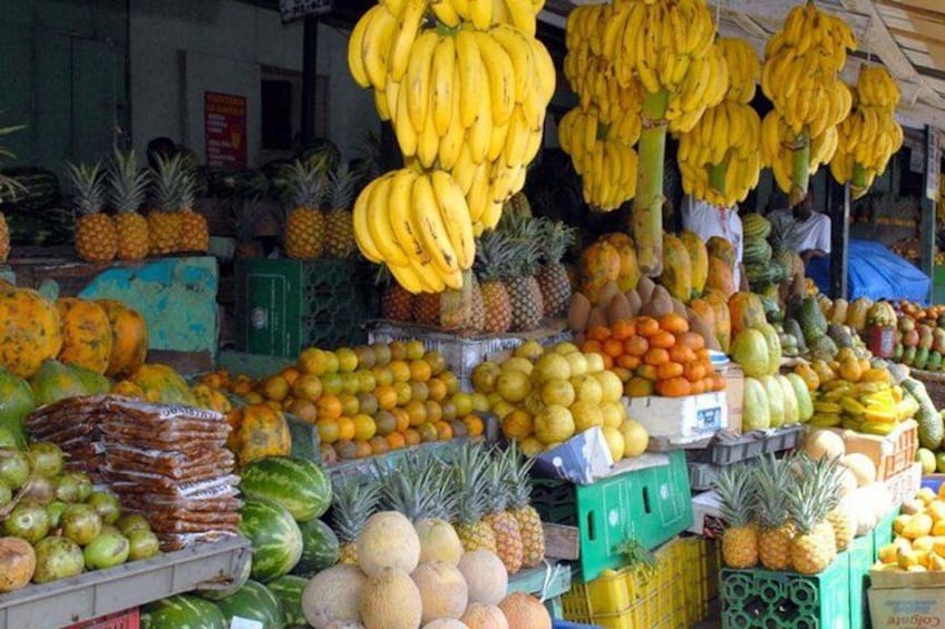 A fruit market with bananas, pineapples, and various other fruits on display. 1