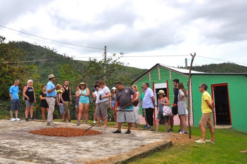 A group of people gathered around a green building with a red door, standing on a concrete platform with scattered objects. 4