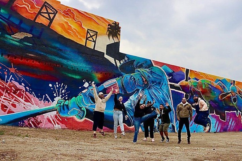 A mural with a large blue elephant and people standing in front of it. 1