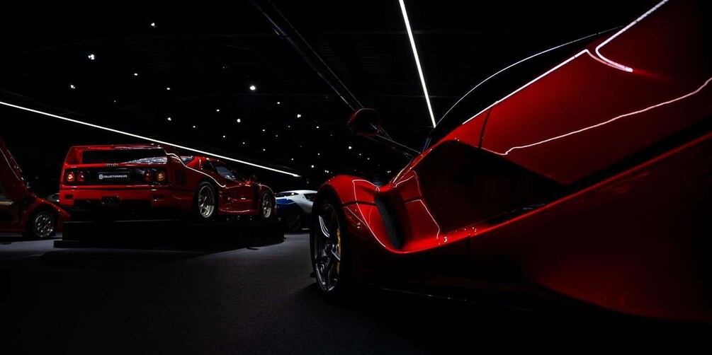 A red sports car in a dimly lit indoor space with other vehicles. 5