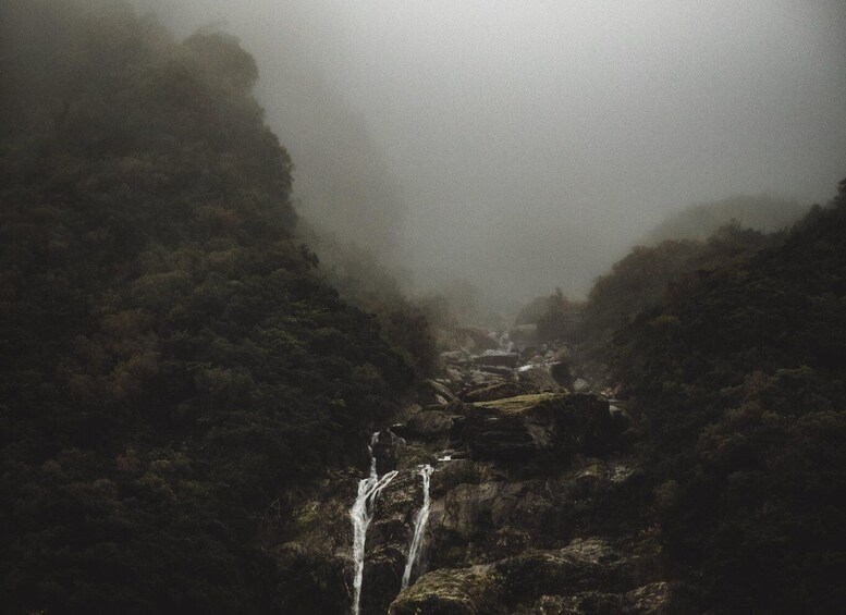 A waterfall cascading down a rocky terrain surrounded by dense forest. 3