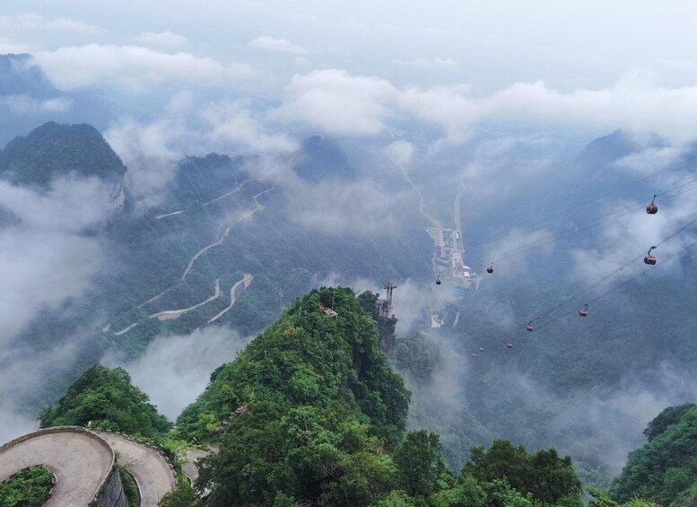 A mountainous landscape with winding roads, cable cars, and a misty atmosphere. 4