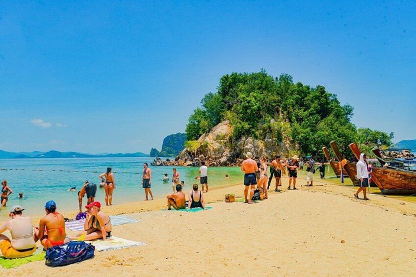A beach with people sunbathing, swimming, and boats on the shore. 1