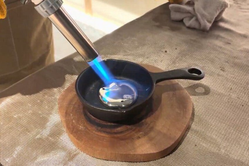 A black pan on a wooden board with a blue flame underneath. 4