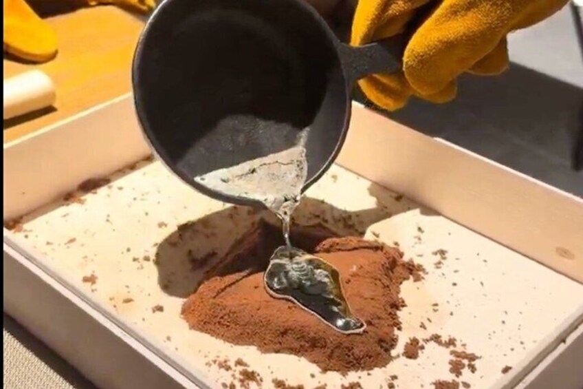 A person pouring a liquid onto a pile of brown powder. 3
