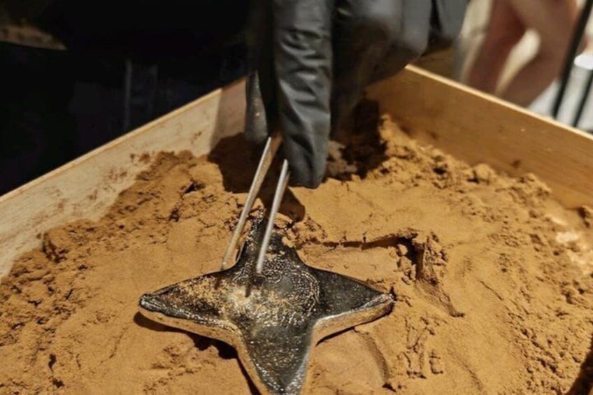 A person using a tool to dig into a pile of sand. 5