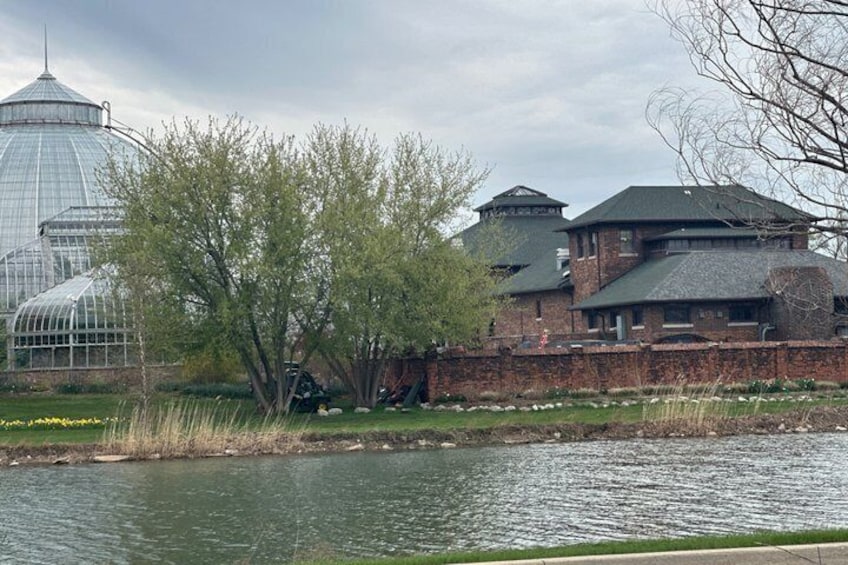 A large brick building with a glass greenhouse and a body of water in the foreground. 5