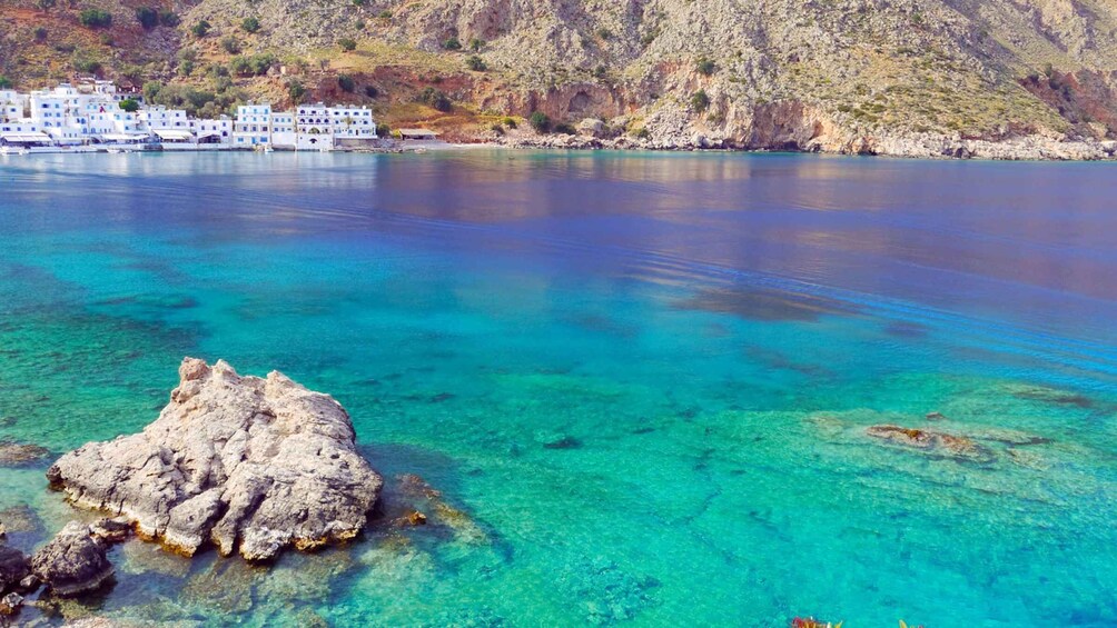 A coastal town with white buildings, clear turquoise waters, and rocky outcrops. 2