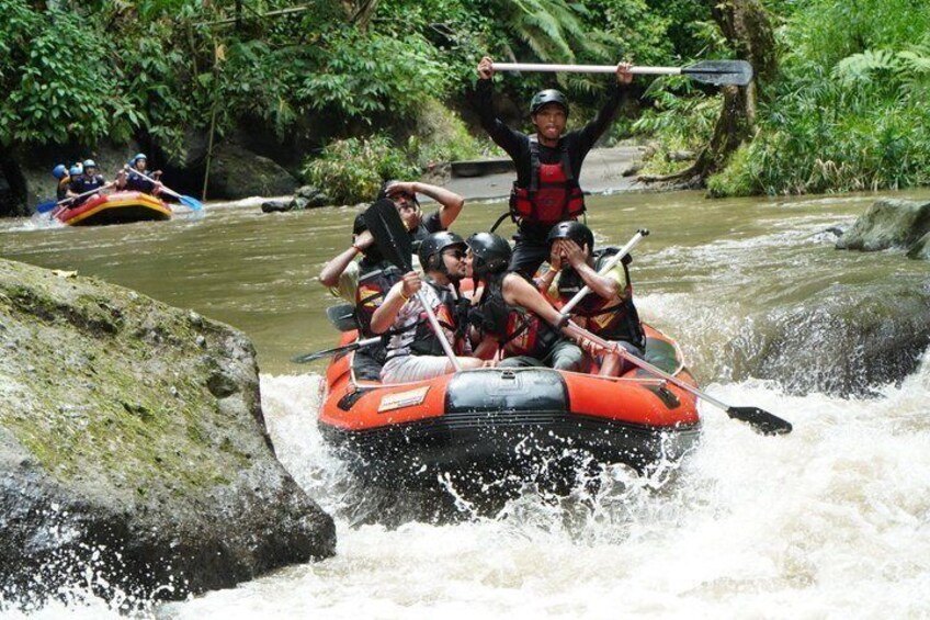Un groupe de personnes fait du rafting sur une rivière bordée de rochers et de végétation luxuriante. 2