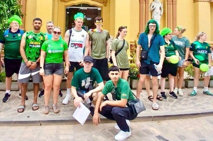 A group of people in green sports attire posing in front of a building with columns. 2