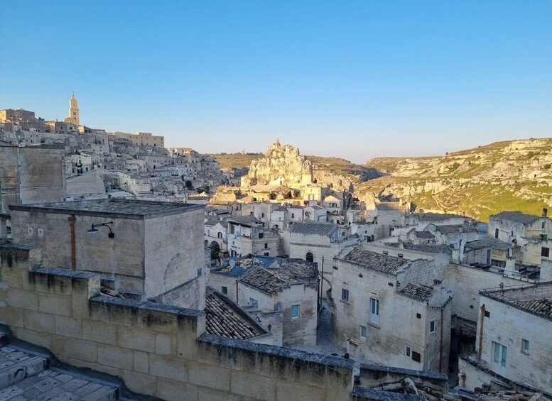 A historic town with stone buildings, a prominent church, and a rocky hill in the background. 1