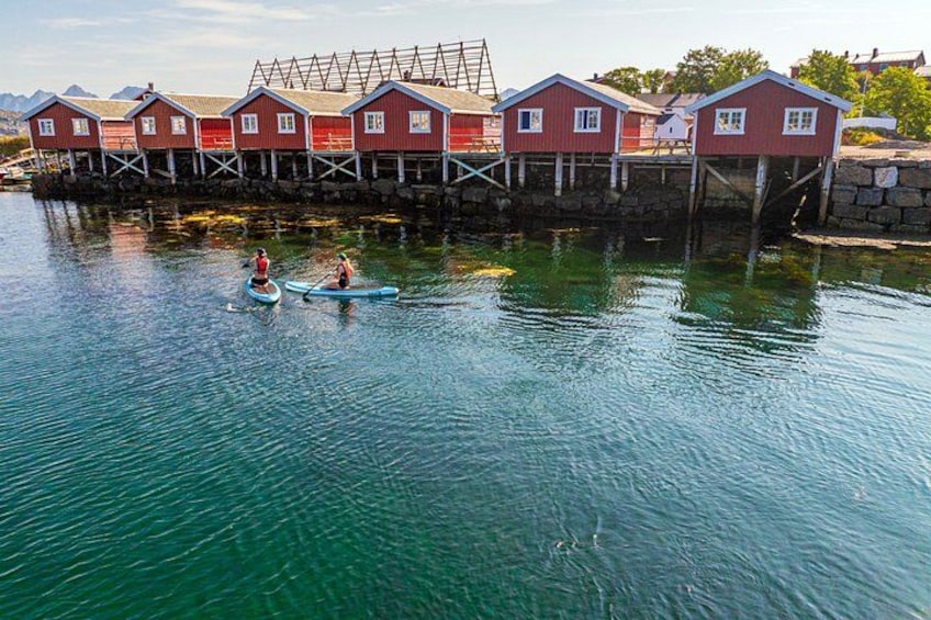 A row of red wooden houses on stilts by a calm body of water. 3