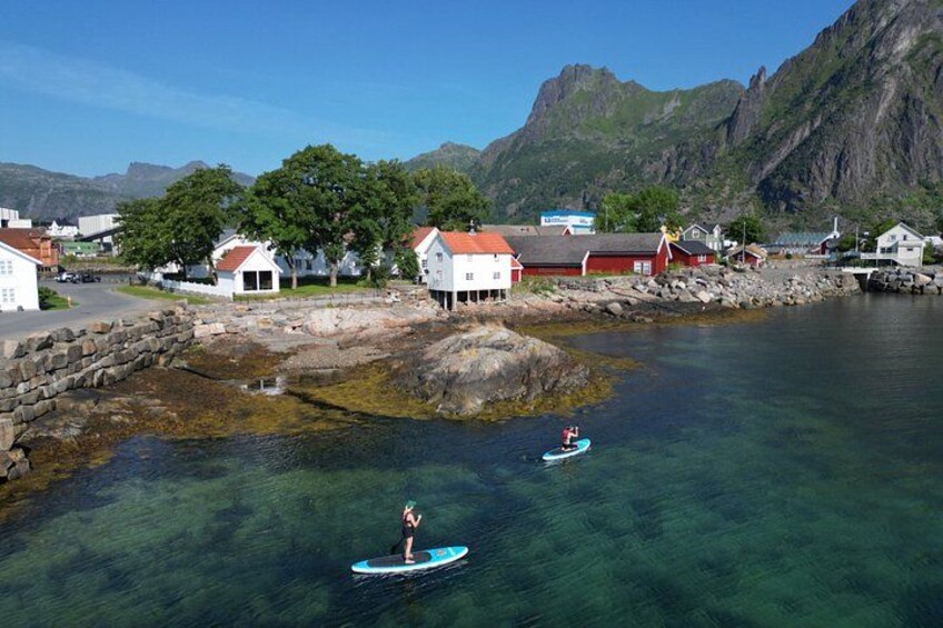 A coastal village with houses, a rocky shore, and kayakers on the water. 4