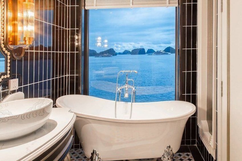 A bathroom with a freestanding bathtub, a vanity with a mirror, and a view of the sea. 3
