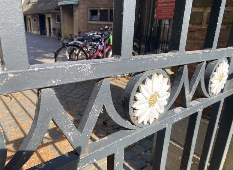 A metal fence with decorative white flowers and a cobblestone street in the background. 4