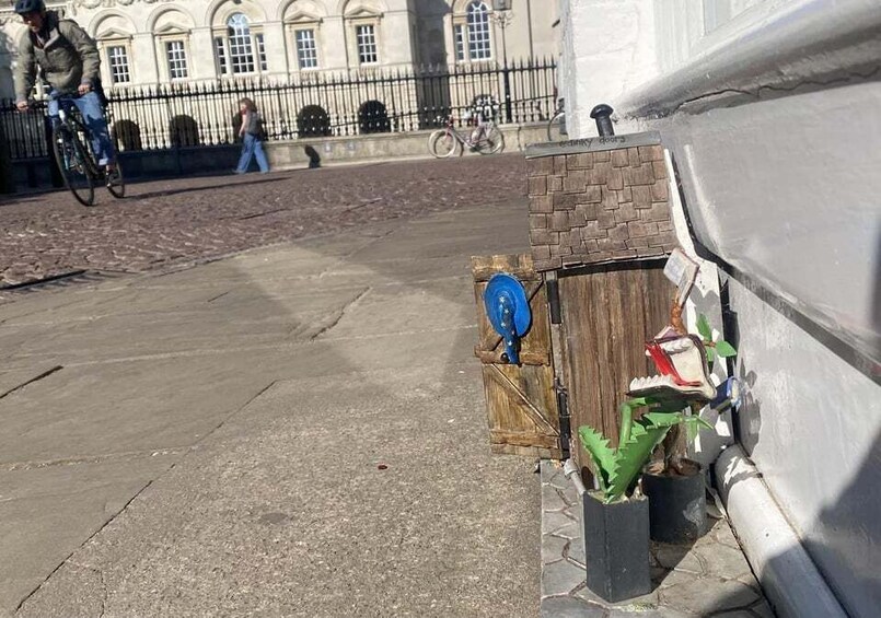 A street with a wooden structure, a blue object, and potted plants. 5