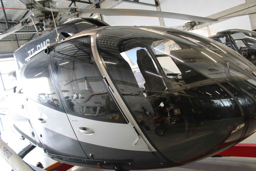 A helicopter with 'ZT-DMC' on its side, suspended in a hangar. 2