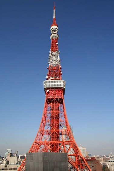 A red tower with a spire, surrounded by city buildings. 3