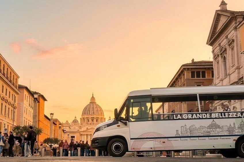 Ein Bus mit der Aufschrift 'LA GRANDE BELLEZZA', der an einer Straße steht, an der Menschen stehen. 1