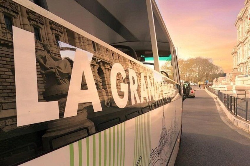 Ein Bus mit der Aufschrift 'LA GRANDE', der an einer Straße mit Gebäuden im Hintergrund geparkt ist. 2