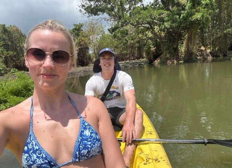 A person in a blue patterned swimsuit and another in a white t-shirt on a yellow kayak. 2