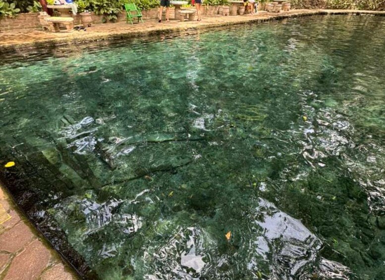 A clear pool with visible underwater rocks and a paved edge. 3