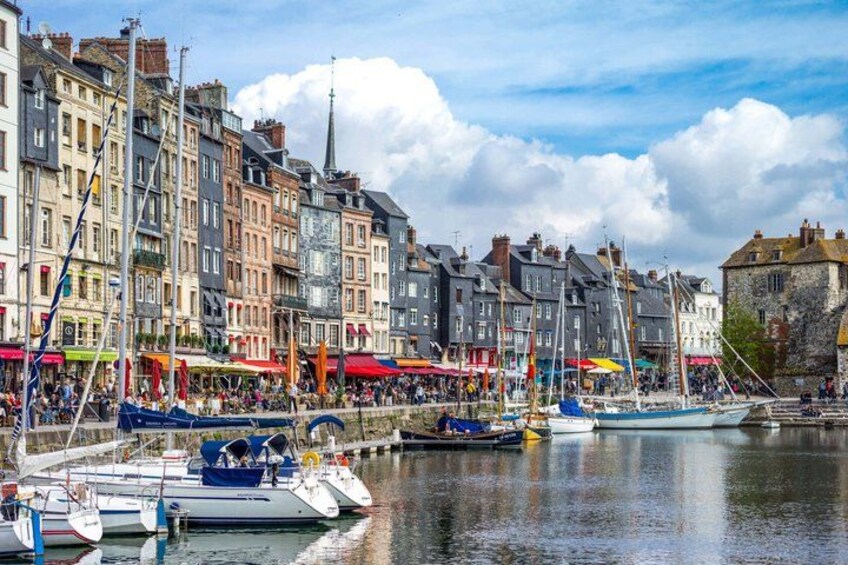 A waterfront with boats docked, historic buildings, and a clear sky. 3