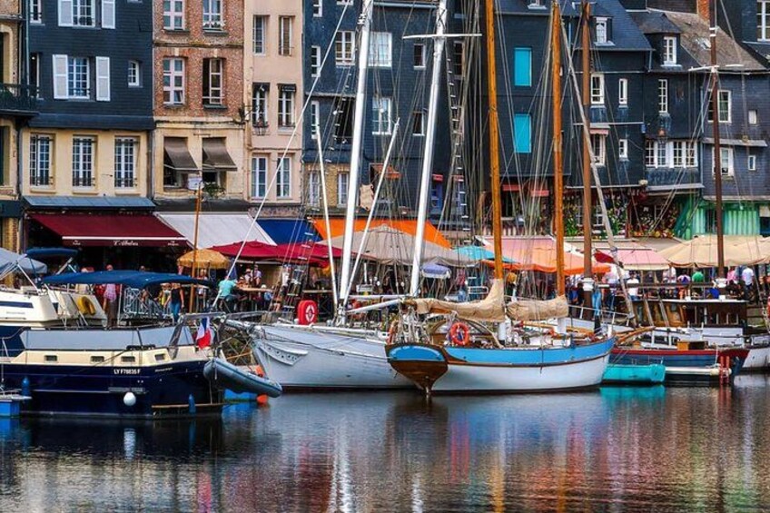 A harbor with several boats docked, a variety of buildings, and a crowd of people. 2