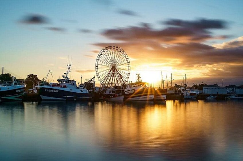 A marina with boats, a large Ferris wheel, and a sunset. 4