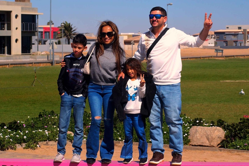 A family posing on a pink platform with a grassy field and buildings in the background. 2
