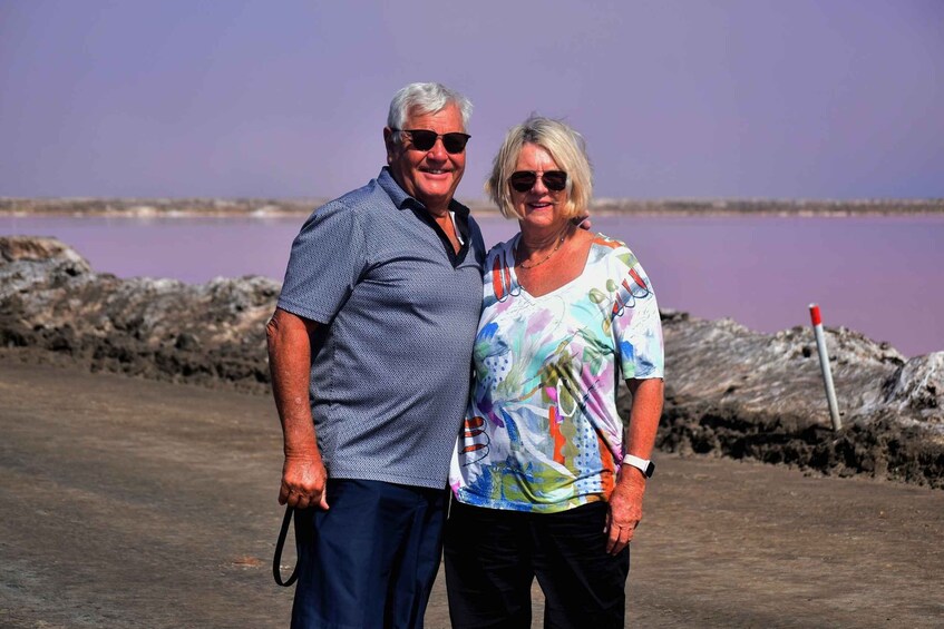Two people standing by a body of water with a rocky shoreline. 4