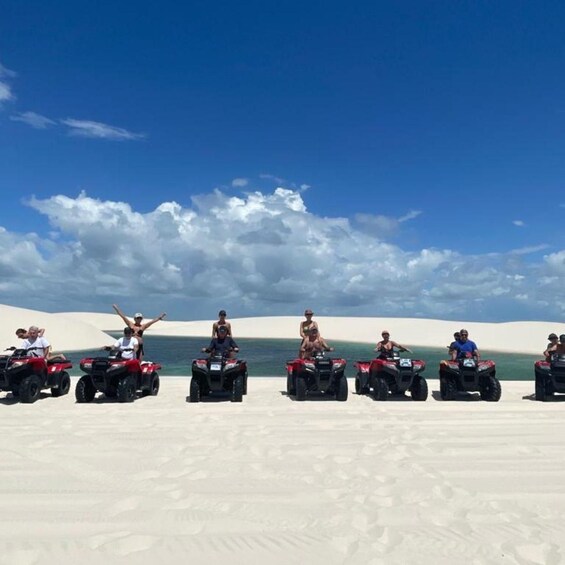 A group of people on quad bikes in a desert landscape with sand dunes and a clear sky. 3