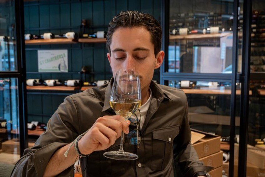 Iemand houdt een wijnglas vast in een modern interieur, met planken en dozen op de achtergrond. 5