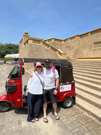 Two people standing next to a red tuk-tuk with a sign that reads 'Ceylon Travel.' 2