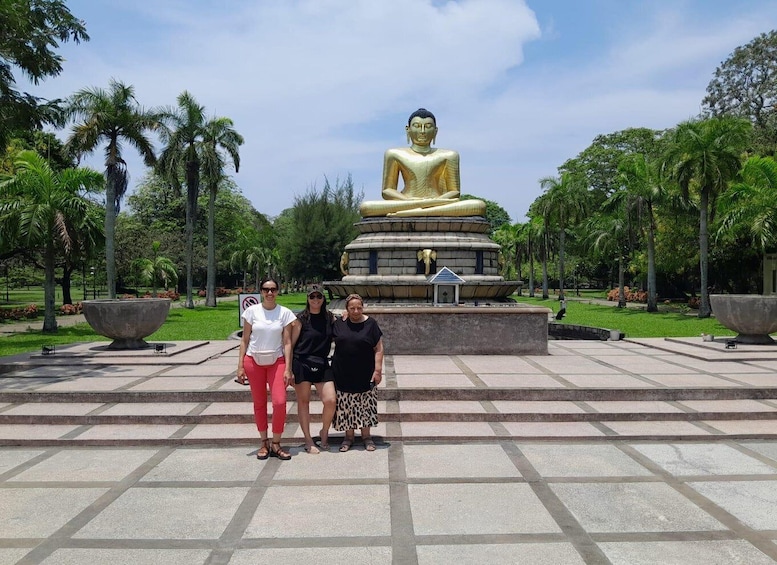 A large golden Buddha statue in a park with palm trees and a fountain. 5