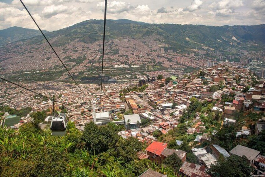 Paesaggio urbano con un sistema di funivia, edifici residenziali densi e colline circostanti. 4