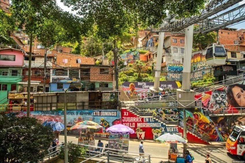 Vivace strada cittadina con murales colorati, un autobus e una scala che conduce verso un pendio. 5