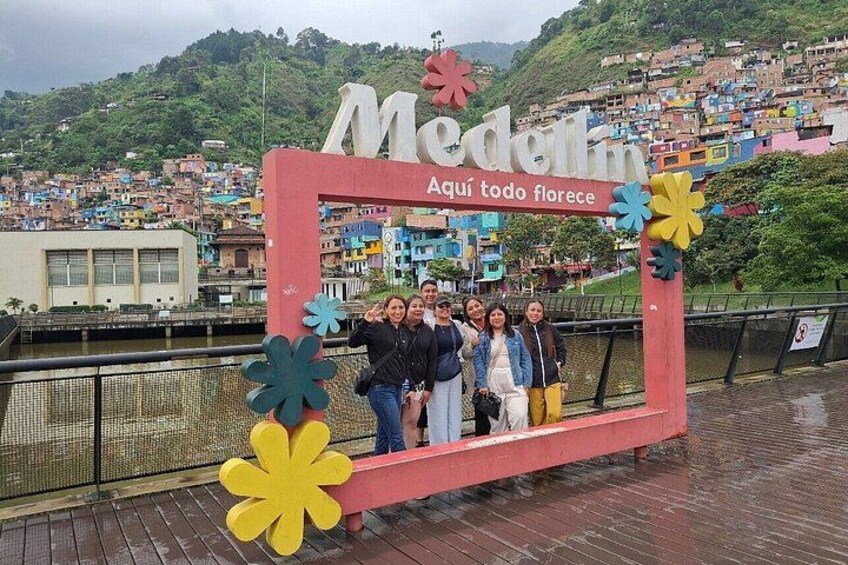 Un grupo de personas posando frente a un letrero colorido con el texto 'Medellín Aquí todo florece'. 2