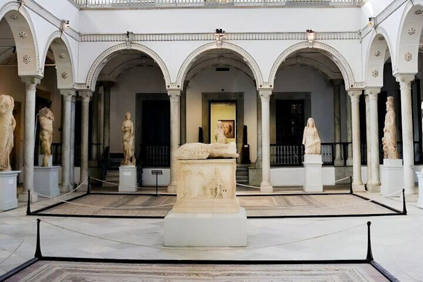 Une cour d’architecture classique, ornée d’arcades, de statues et d’un sarcophage central. 3