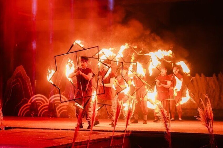 Performers with fire props on a stage with geometric shapes and plants. 4