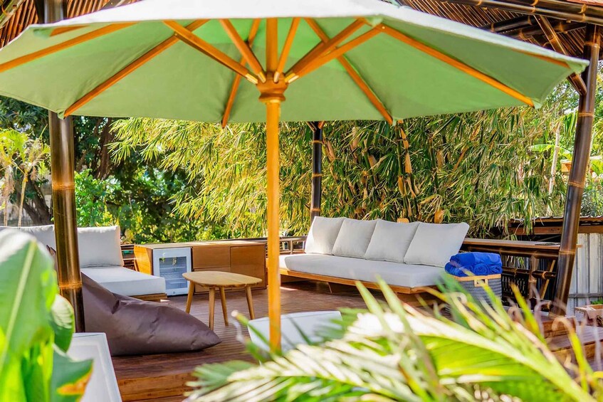 A wooden deck with a white sofa, a table, and a large green umbrella. 3