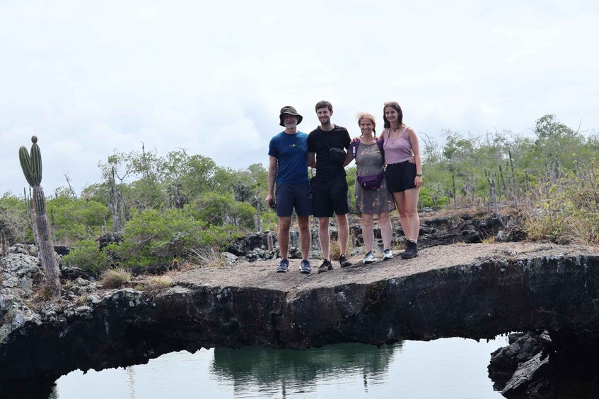 Four people standing on a rocky ledge with a body of water below. 1