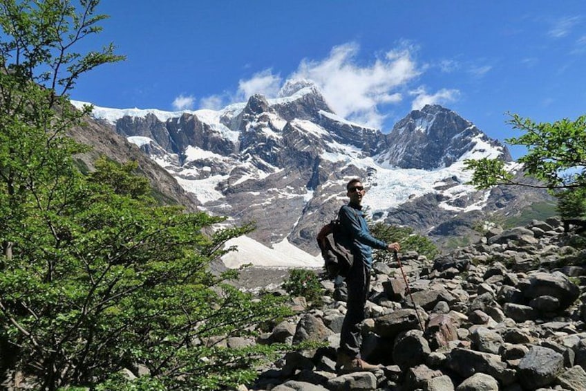 Un excursionista en un sendero rocoso con montañas nevadas al fondo. 2