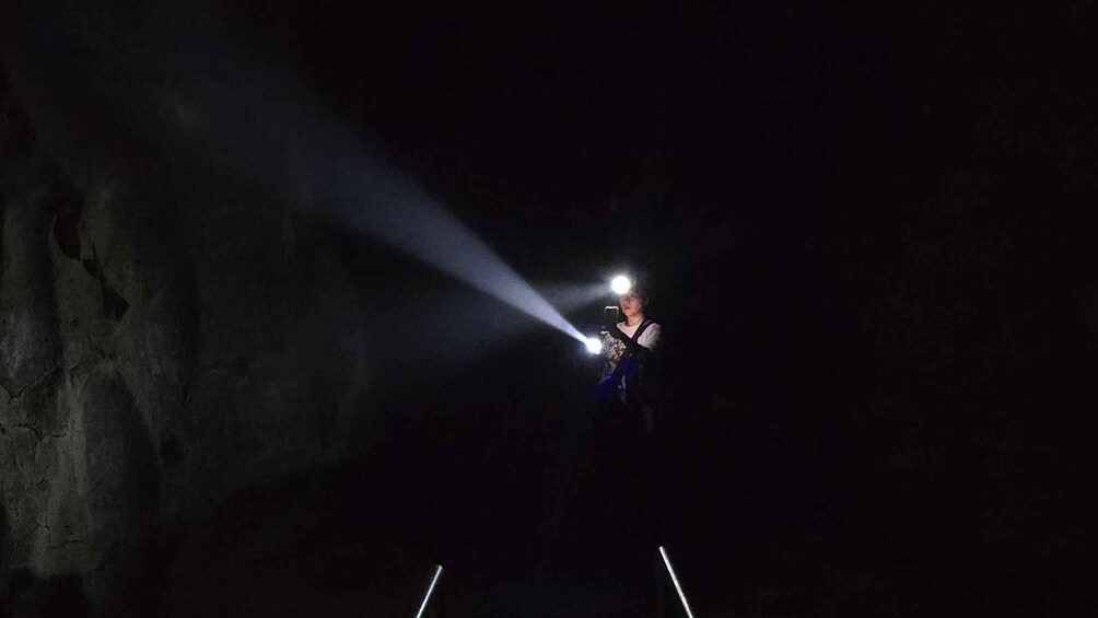 A person using a flashlight in a dark cave. 4