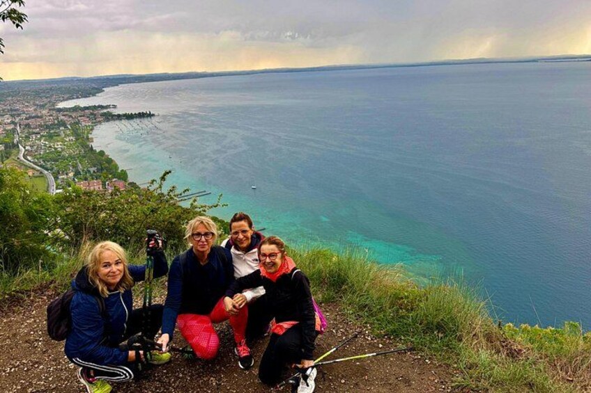 A group of people on a hill overlooking a coastal landscape with a view of the sea and a distant shoreline. 2