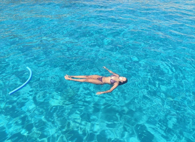 A person floating on a clear blue water body. 4