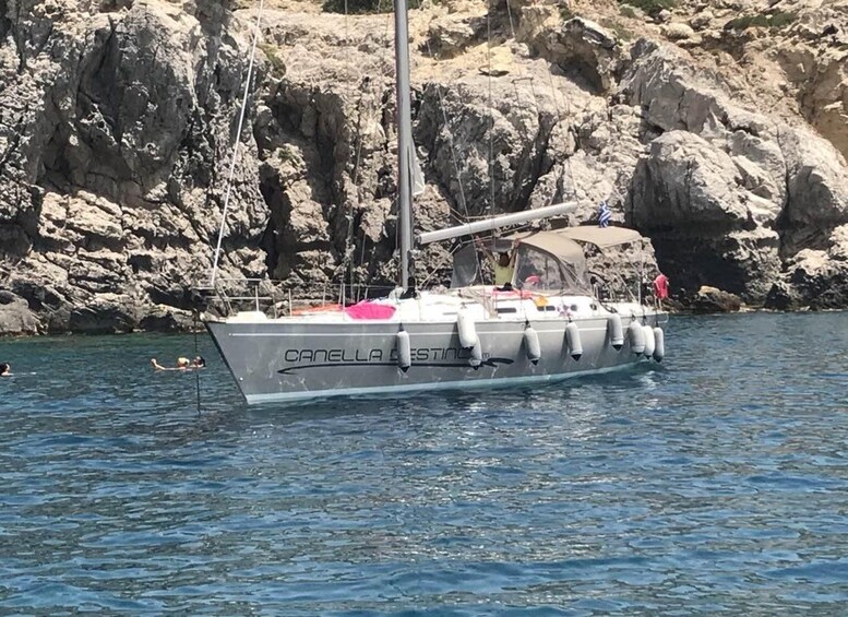 A sailboat named 'CANELLA' anchored near rocky cliffs. 1